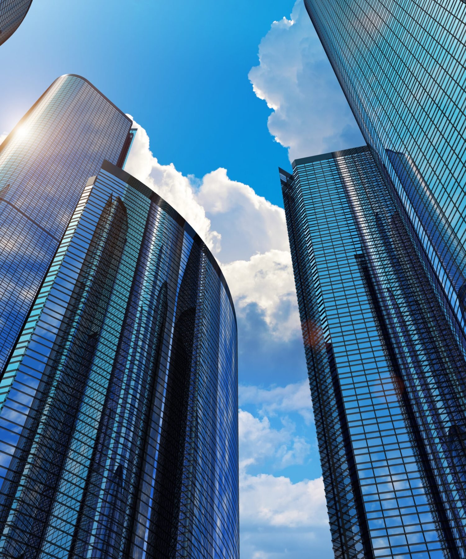 Downtown corporate business district architecture: glass reflective office buildings against blue sky with clouds and sun light